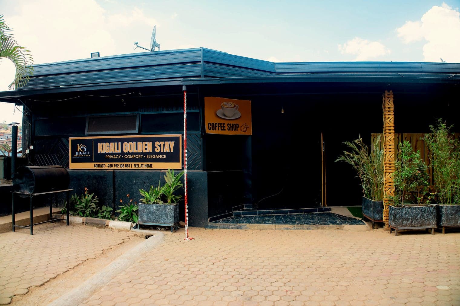 The black facade of Kigali Golden Stay with its gold sign reading Privacy, Comfort, Elegance, and a Coffee Shop sign over the entrance